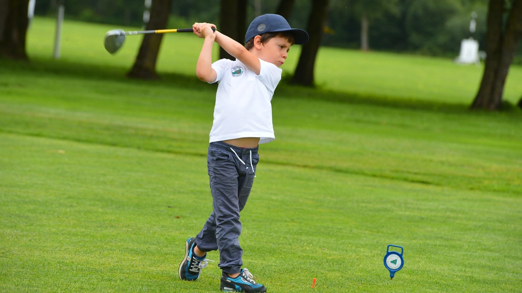 Kleiner Junge beim Golfspielen