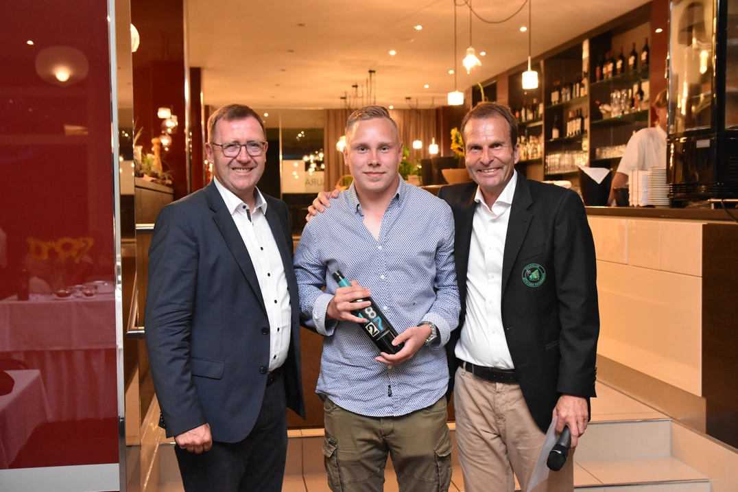 268 Meter weit schlug Moritz Markert seinen „Longest Drive“. Präsident Karl-Friedrich Löschhorn, links, und GF Wolfgang Michel überreichten den Bio-Wein von Costa Navarino als Preis.