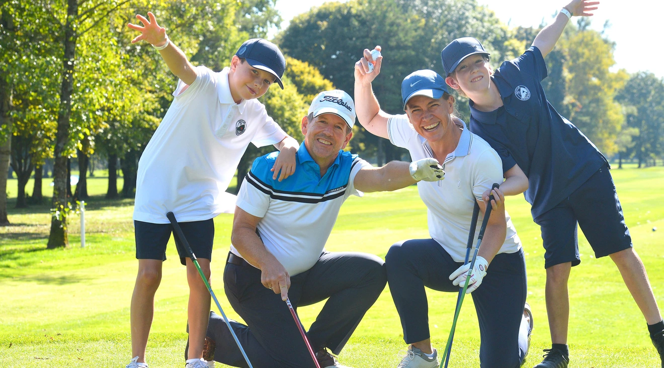 4-köpfige Familie posiert vor Golffahne